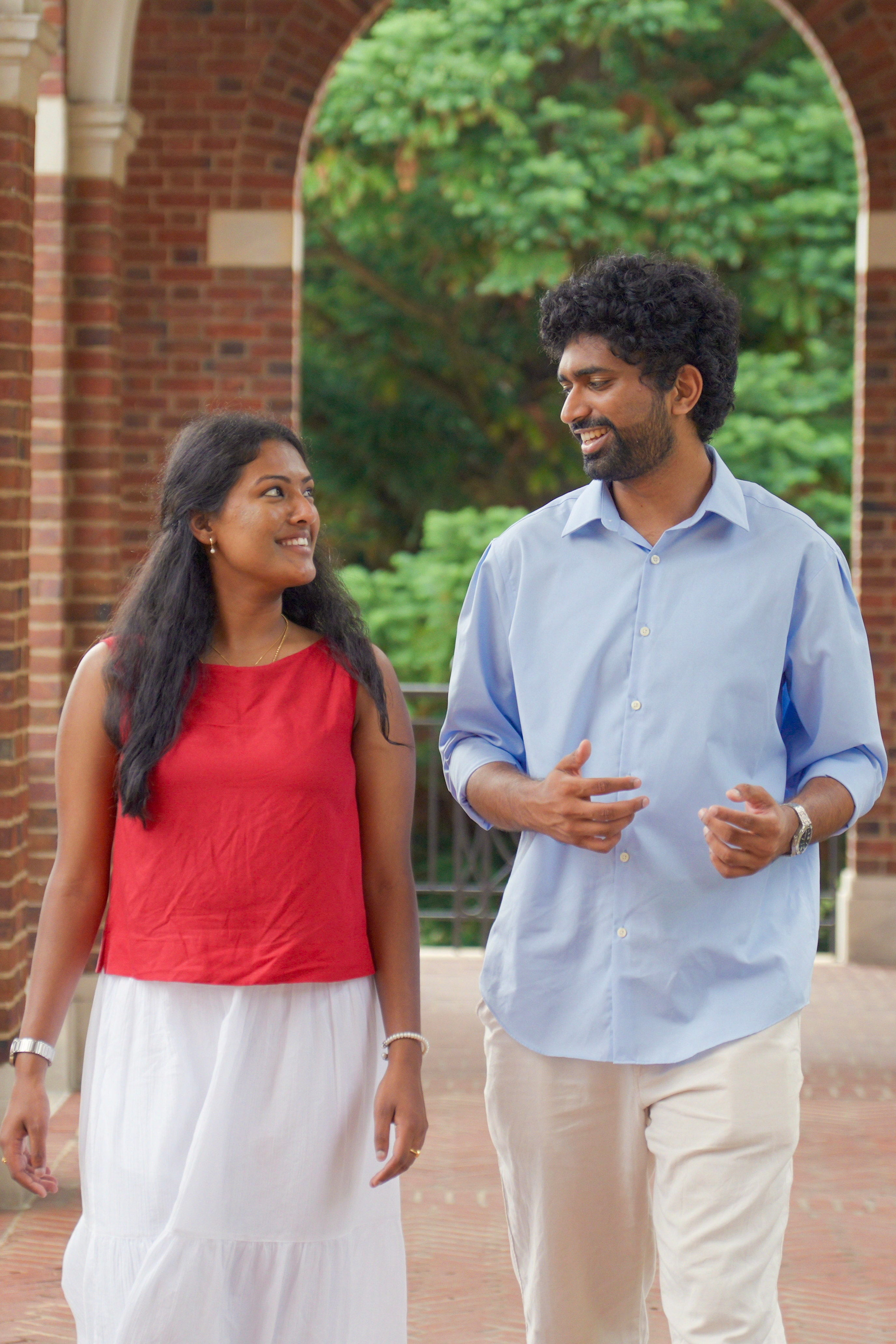 Aarti and Anish walking together under a brick archway at Hopkins